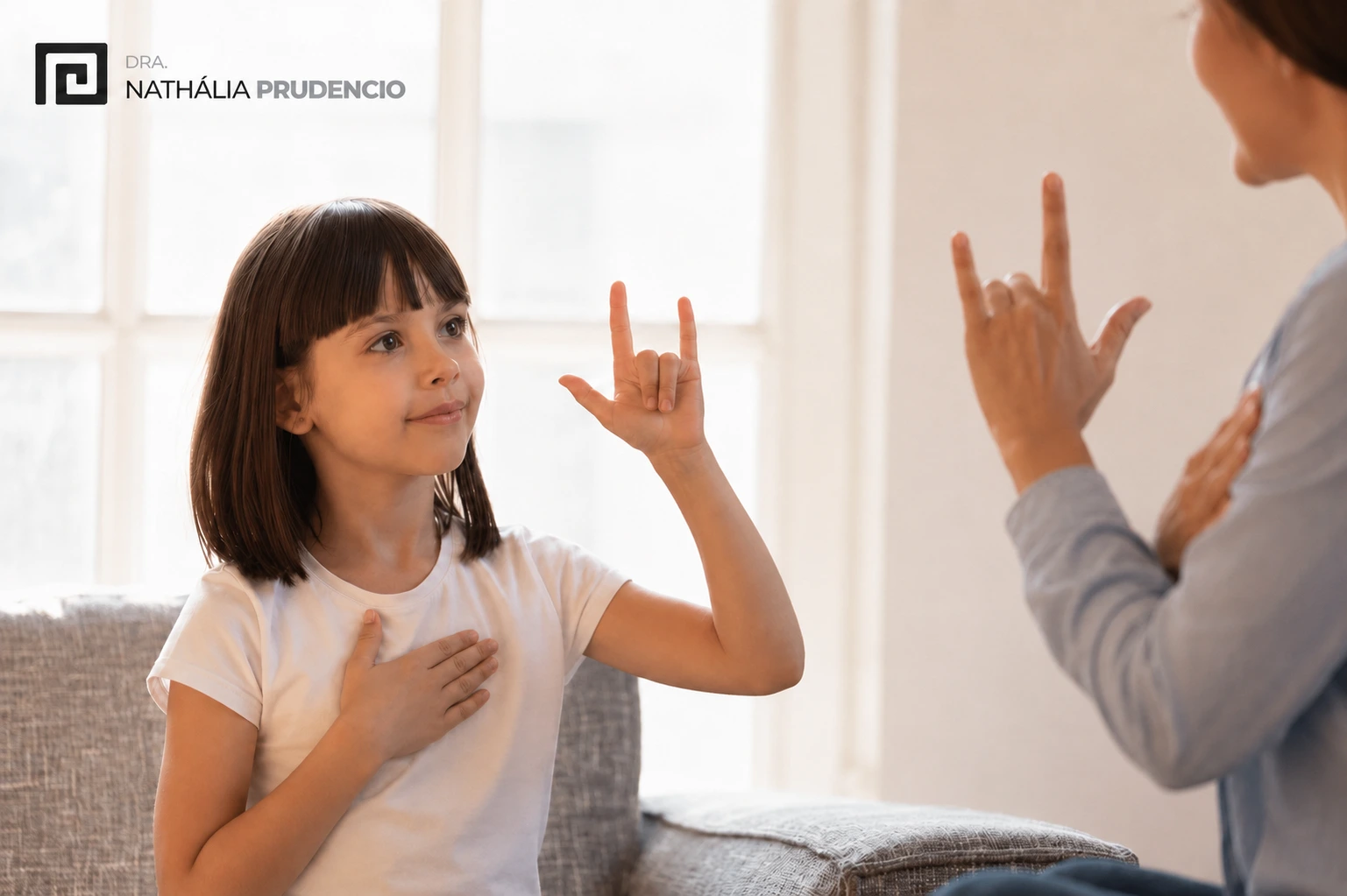 Garotinha aprendendo o sinal "Eu te amo" em Libras
